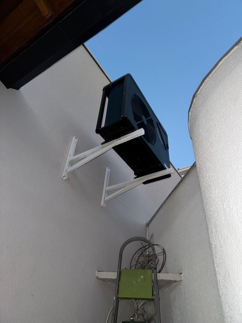 Bomba de calor preta instalada na parede de área externa